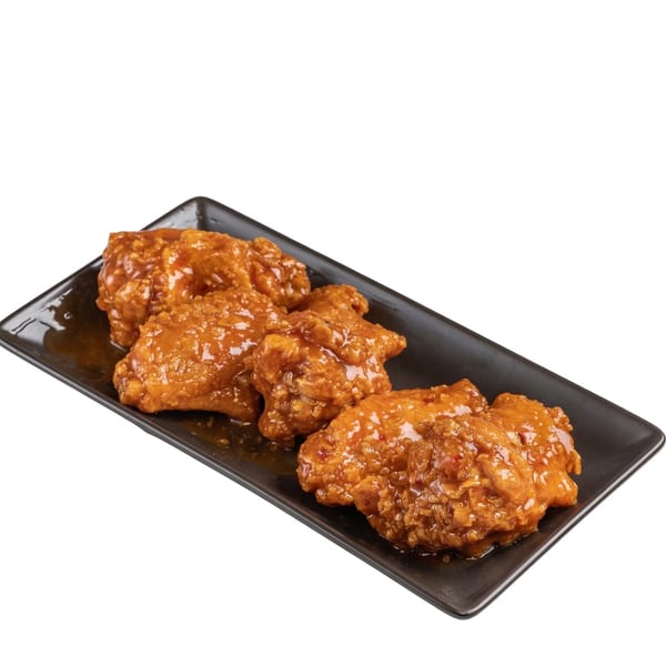 Four crispy, glazed chicken wings covered in a sweet and spicy orange sauce on a black rectangular plate.