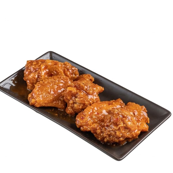 Four crispy, glazed chicken wings on a black rectangular plate, coated in a sweet and spicy sauce.