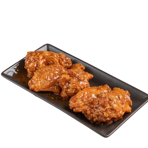 Four crispy chicken wings coated in a glistening orange sauce, served on a black rectangular plate.